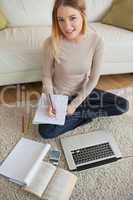 Woman doing homework and sitting on floor using laptop
