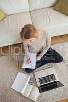 Blonde doing homework and sitting on floor using laptop
