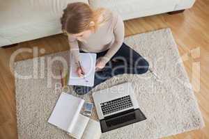 Young woman doing homework and sitting on floor using laptop