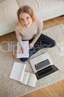 Happy woman doing homework and sitting on floor using laptop