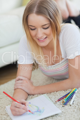Happy woman lying on floor sketching on paper