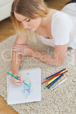 Happy young woman lying on floor sketching on paper