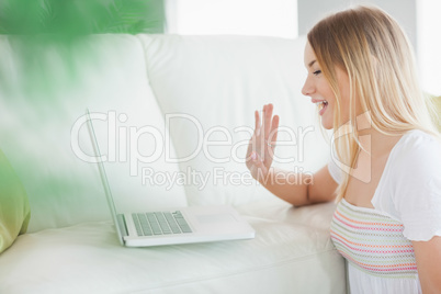 Woman sitting on floor calling with laptop