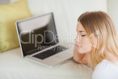 Thoughtful woman sitting on floor in front of laptop