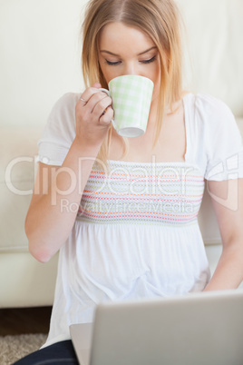 Woman drinking coffee while using laptop