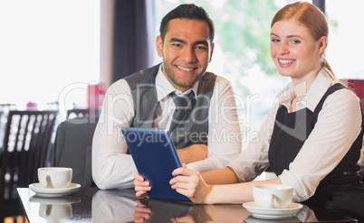 Business team working on tablet pc together in a cafe