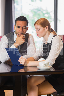 Business partners working on tablet pc together in a cafe