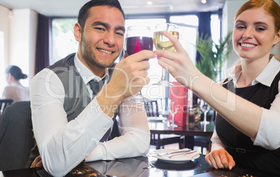 Smiling business partners clinking wine glasses looking at camer