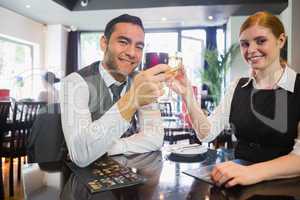 Happy business partners clinking wine glasses smiling at camera