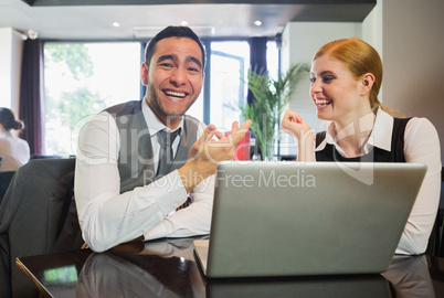 Laughing business people working on laptop