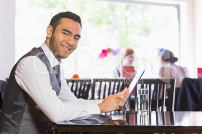 Happy businessman using tablet and smiling at camera