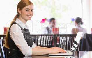 Smiling businesswoman working on laptop looking at camera