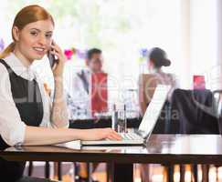 Smiling businesswoman looking at camera while calling on phone