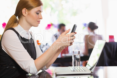 Concentrated businesswoman sending a text