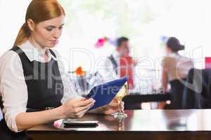 Businesswoman looking at tablet screen while holding wine glass