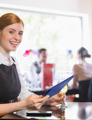 Happy businesswoman holding tablet and wine glass looking at cam