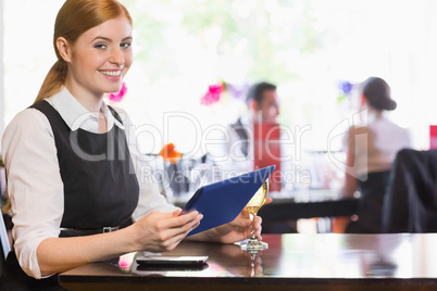 Smiling woman using tablet while holding wine glass and looking