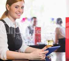 Attractive businesswoman holding tablet and wine glass and smili