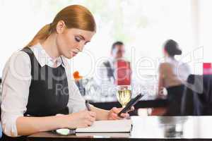 Concentrated businesswoman holding phone while writing