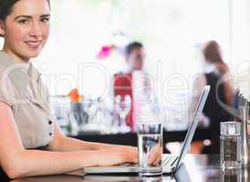 Smiling businesswoman working on laptop while looking at camera