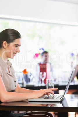 Smiling businesswoman working and laptop and looking on screen