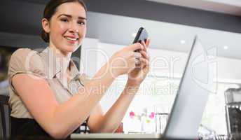 Smiling businesswoman holding phone looking at camera