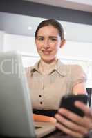 Smiling businesswoman holding her phone in a cafe