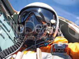military pilot in the plane in a helmet in dark blue overalls ag