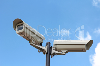 two security cameras against blue sky