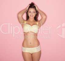 sexy woman with a lovely body standing posing in yellow lingerie and twiddling her long brunette hair in her fingers, three quarter studio portrait