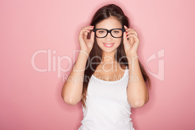 thoughtful shapely brunette woman wearing lingerie and glasses standing looking sideways with a pensive expression against a pink background