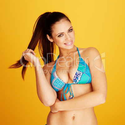 smiling brunette woman posing with her blue bikini swim suit
