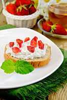 bread with curd cream and strawberries on a board