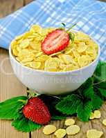 corn flakes in bowl with strawberries on a board