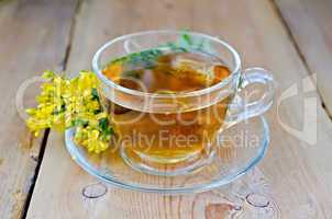herbal tea from tutsan in a glass cup on a board