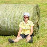 Farmer sitting in front of hay bales