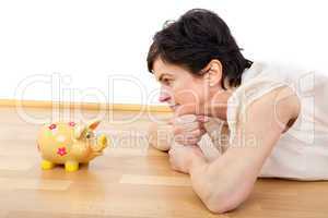 Woman looks thoughtfully at the piggy bank