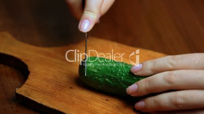 female hand cuts cucumber