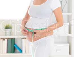 Pregnant woman measuring her belly