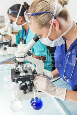 Female Scientific Research Team Using Microscopes in Laboratory