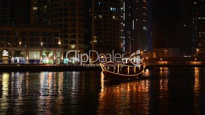 The night illumination of Dubai Marina and Dhow boat. It is an artificial canal city, built along a two mile (3 km) stretch of Persian Gulf shoreline. Dubai, UAE