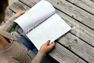 Young woman sitting at the table with a booklet