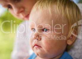 portrait of a crying little boy who is being held by her mother