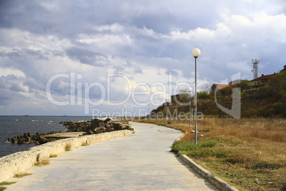 the road along the sea on a background of dark clouds