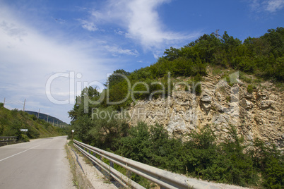 asphalt road in mountains against the blue sky with white clouds