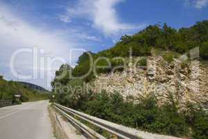 asphalt road in mountains against the blue sky with white clouds