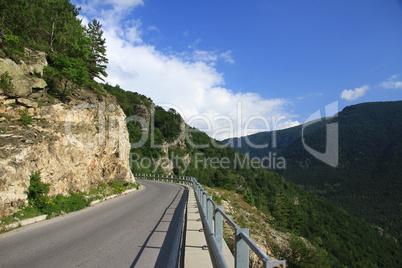 asphalt road in mountains against the blue sky with white clouds
