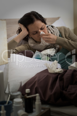 Sick woman with flu sneezing in bed