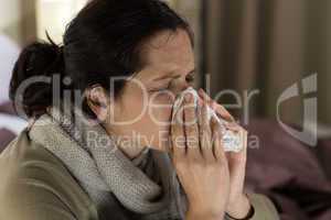Ill woman sneezing in a tissue