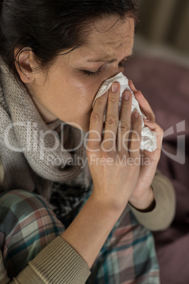 Portrait of woman sneezing into tissue